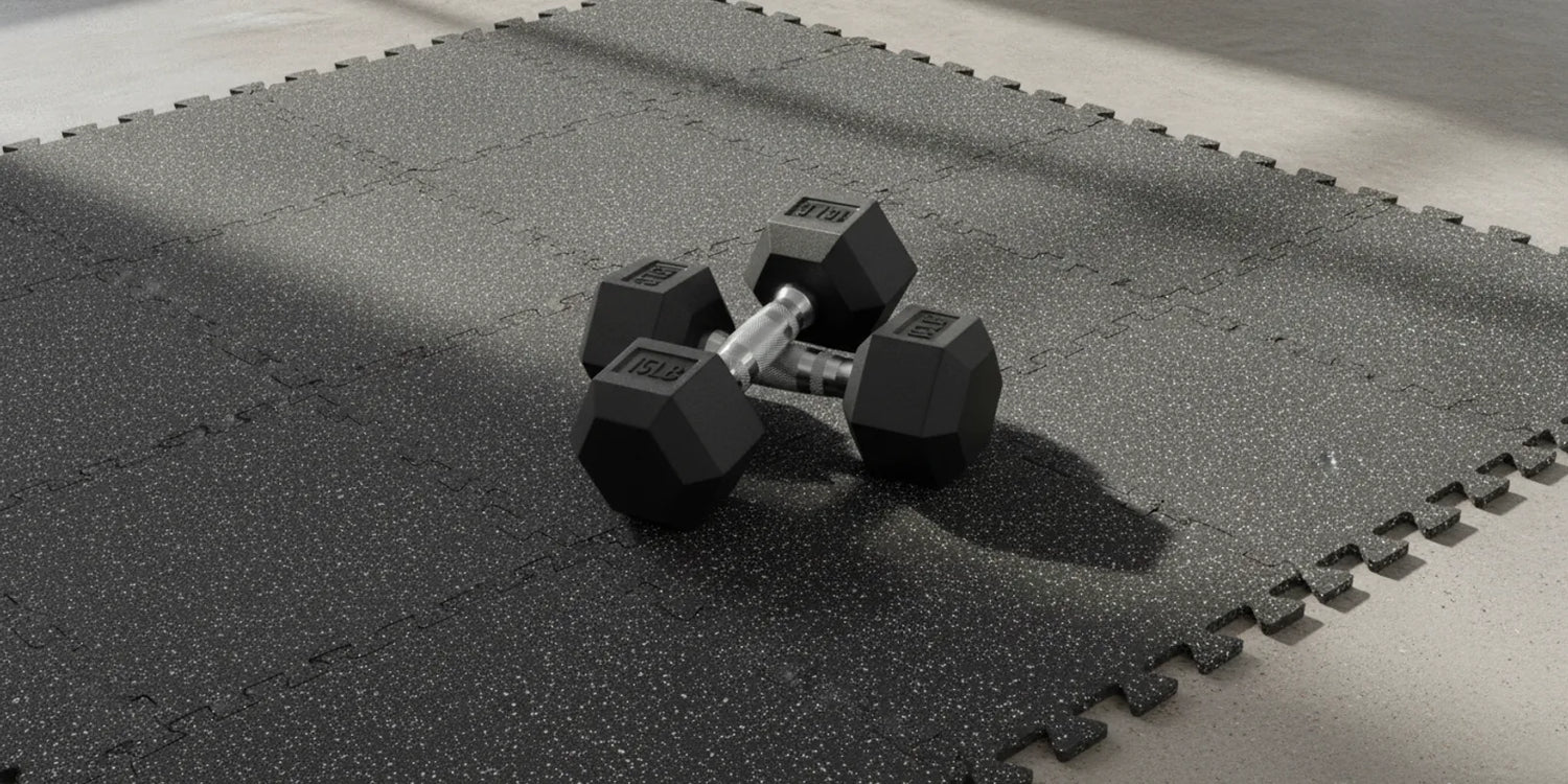 RitFit rubber interlocking gym flooring mats installed over a concrete floor with hex dumbbells