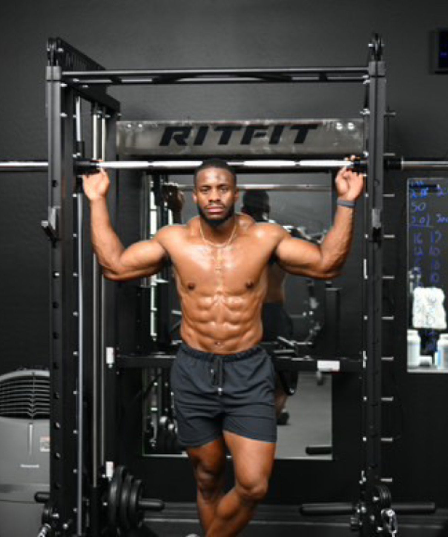 Jarell Carter posing with a black Ritfit power rack in a home gym