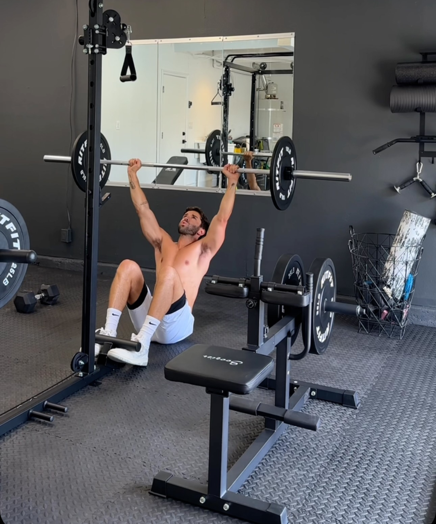 Man lifting barbell in Jake Miller's home gym with black weightlifting equipment