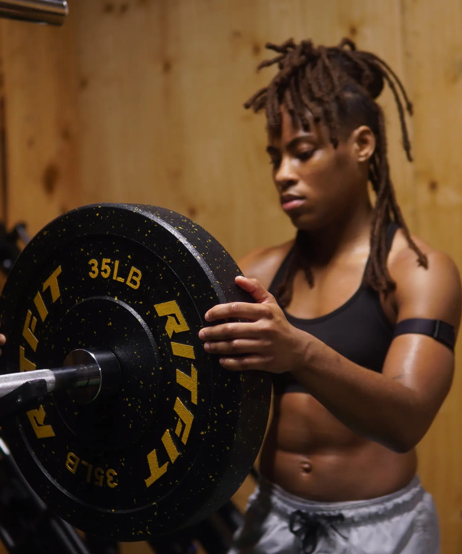 Kiaya Jackson adjusting a black RitFit 35lb barbell plate in her home gym