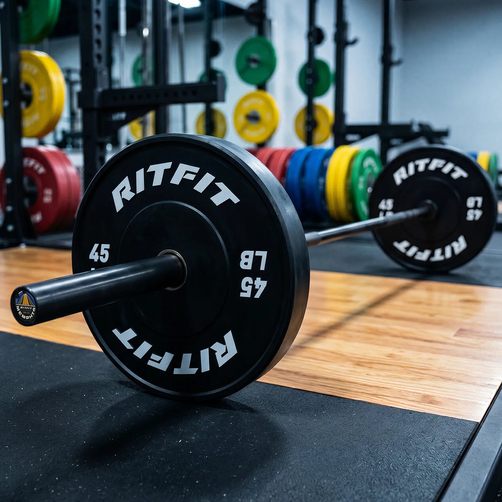 RitFit solid black Olympicbarbell with 45 lb bumper plates on gym floor