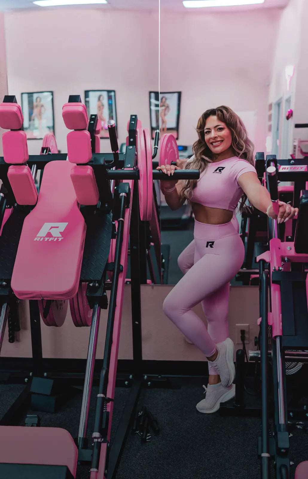 Woman in pink athletic wear posing in a gym with pink equipment