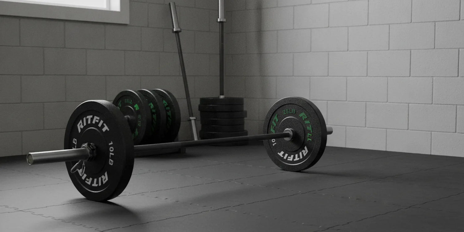 RitFit budget bumper plates stacked with a solid black Olympic barbell in a home gym