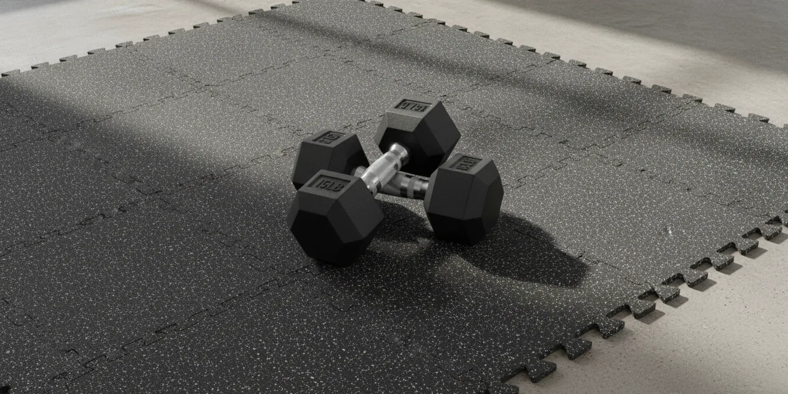 RitFit rubber interlocking gym flooring mats installed over a concrete floor with hex dumbbells
