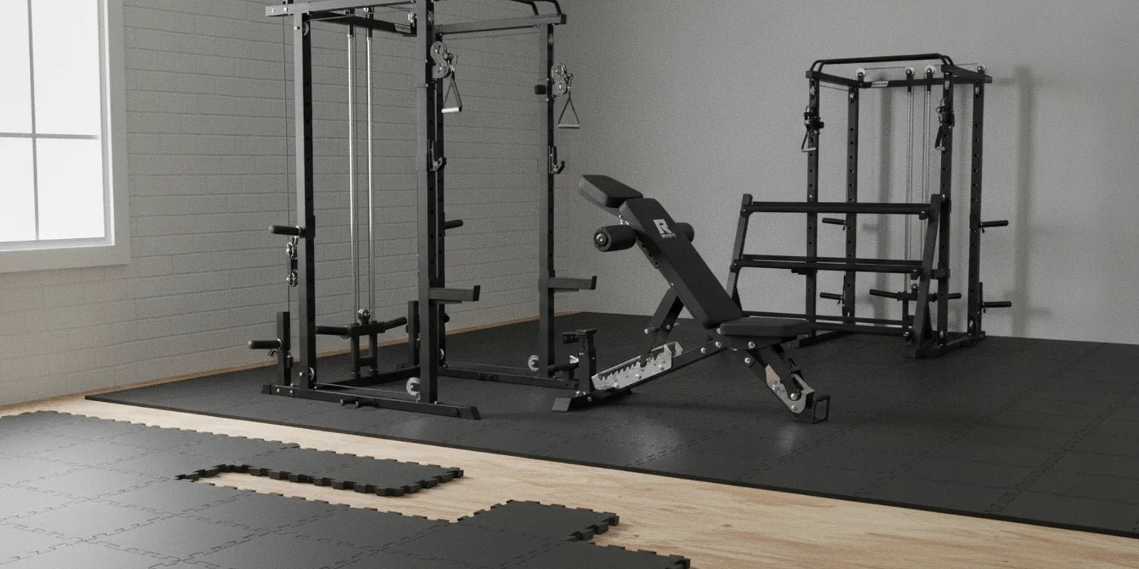 Interlocking rubber gym flooring tiles being laid in a home gym with a power cage and bench