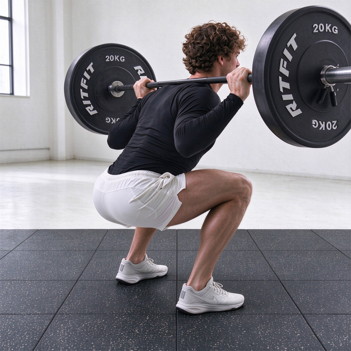 Man squatting with barbell on black RitFit Premium 0.8 inch interlocking rubber gym floor tiles