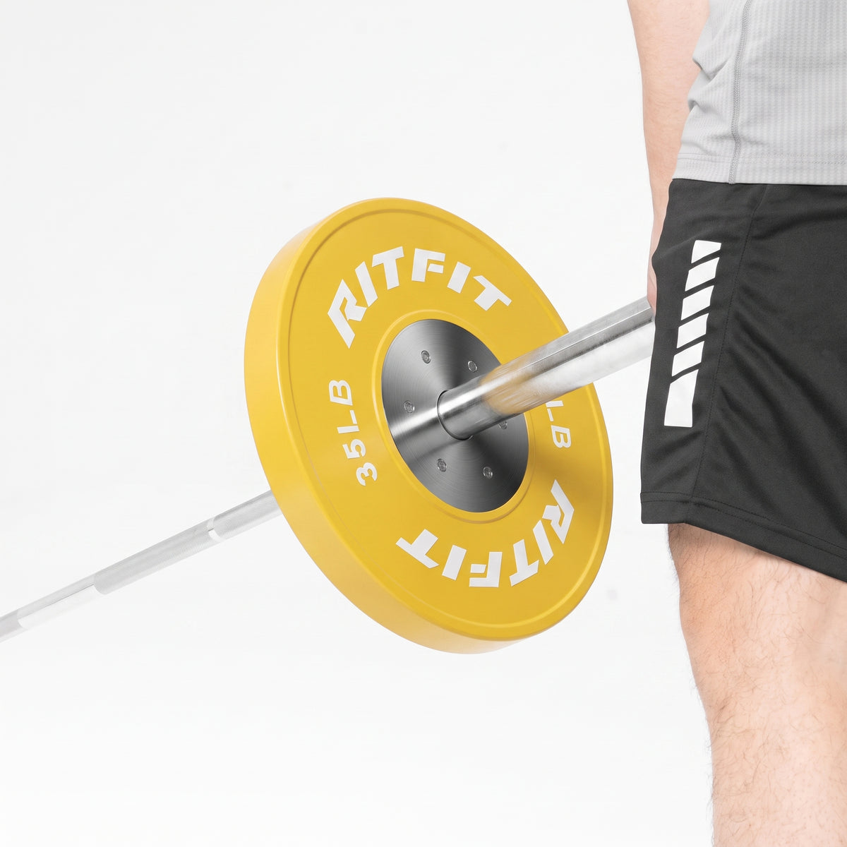 Yellow RitFit 35LB bumper plate on barbell held by athlete in black shorts